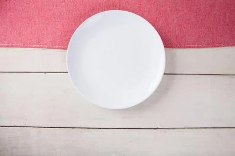 Top view of empty white plate put on red tablecloth and white wood table with Stock Photos