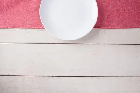 Top view of empty white plate put on red tablecloth and white wood table with Stock-Fotos