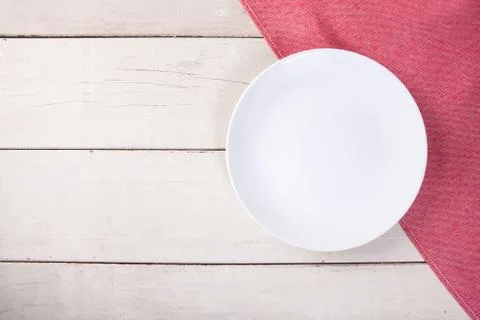 Top view of empty white plate put on red tablecloth and white wood table with Stock Photos