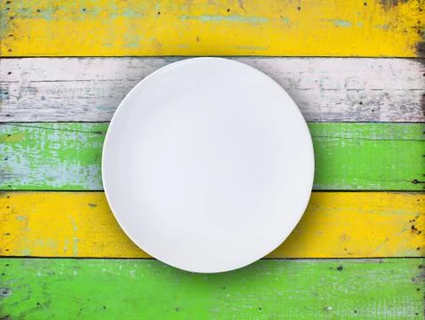 Top view of empty white plate put on colorful wood table with space for copy. Stock Photos