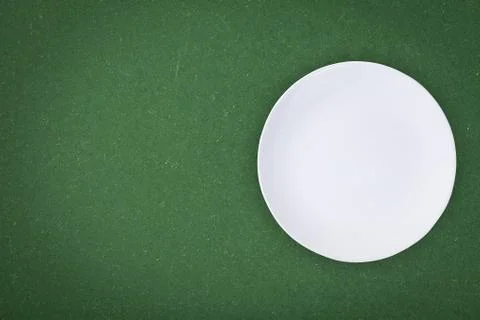 Top view of an empty white plate placed on a blackboard with copy space. Stock-Fotos