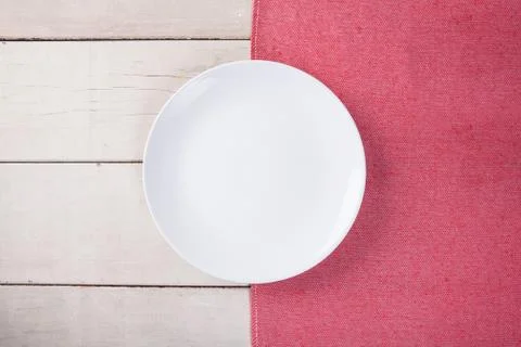 Top view of empty white plate put on red tablecloth and white wood table with Stock Photos