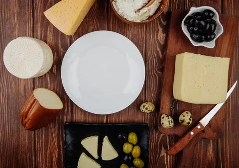 Top view of an empty white plate and different kind of cheese with pickled .. Stock Photos