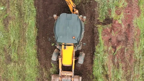 Top view of excavator working in field. Clip. Bulldozer clears plot of land with Stock Footage 249282298