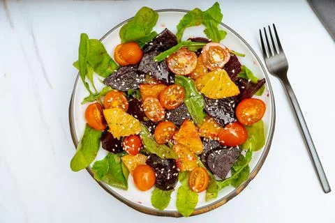 Top view of exquisite salad of beetroot, orange, cherry tomato and arugula wi Stock Photos