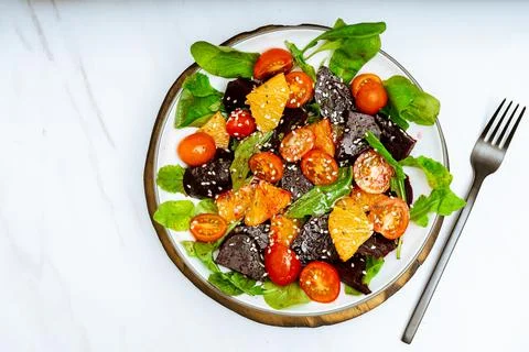 Top View of exquisite salad of beetroot, orange, cherry tomato and arugula wi Stock Photos