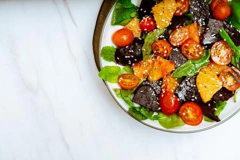 Top view of exquisite salad of beetroot, orange, cherry tomato and arugula wi Stock Photos
