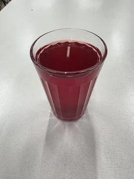 Top view of a faceted glass filled with red berry compote on a light grey table. Stock-Fotos