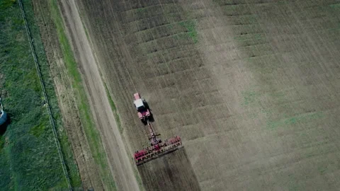 Top view of farmer on a red tractor plows the land in his small plot. Work for Stock-Footage 157674493