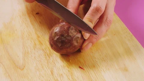 Top view, female hand cuts fruit with a knife on a wooden board, maracuya. The Stock Footage 100255820