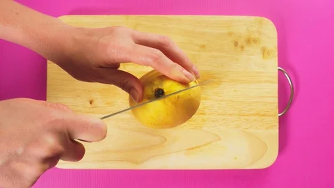 Top view, female hand cuts fruit with a knife on a wooden board, rotten mango Stock Footage 100256306