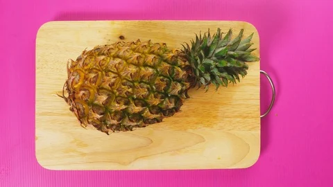Top view, female hand cuts the fruit with a knife on a wooden board, pineapple Stock Footage 100256541