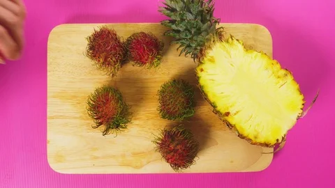 Top view, female hands clean rambutan on a wooden board. The concept of natural Stock Footage 100409772
