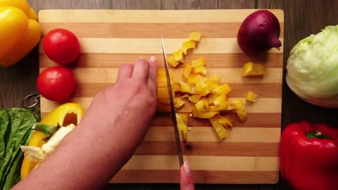 Top view of the female hands cutting a yellow pepper on the little cubes Stock Footage 251457360
