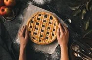 Top View Of Female Hands Holding Apple Pie On Baking Paper Stock Photos