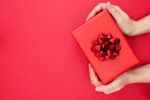 Top view of female hands holding gift box with red ribbon bow isolated over f Stock-Fotos