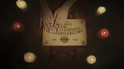 Top view of a female hands moving over the spirit ouija board game, reading the Stock Footage 248005317