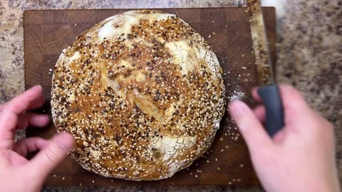 Top view of female hands slicing a round loaf of homemade sourdough bread. 動画素材 344559837