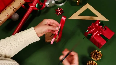 Woman's hands using scissors to cut Christmas wrapping paper Stock