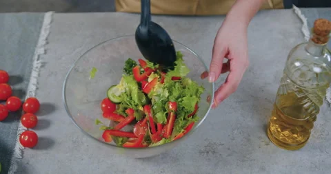 Top view of female hands which mixing fresh vegetable salad applying spoon in Stock Footage 148747520