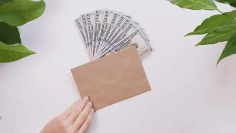 Top view. Female hands write on the envelope the word Bonus. Nearby are money. Stock Footage 130906688