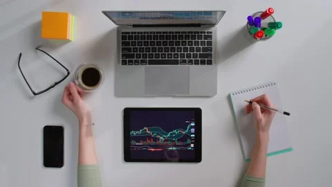 Top view of female looking at tablet with graphs and writing notes having stock Stock Footage 181139728