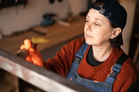 Top view female painter applying black paint metal structure using brush in.. Stock Photos