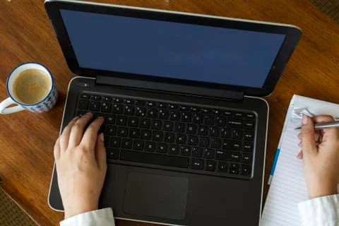 Top view of female using her laptop on a wooden table. Overhead shot of young Stock Photos