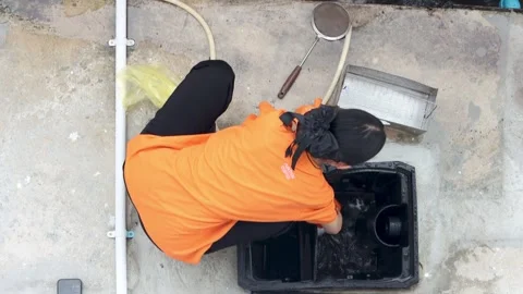 Top view of a female worker cleaning an outdoor grease trap and drainage Stock Footage 345787445