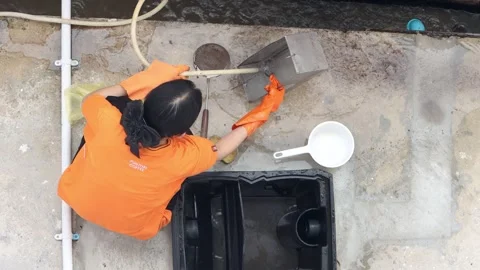 Top view of a female worker washing a metal filter basket from a grease trap Stock Footage 343975440
