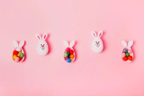 Top view festive Easter pink background with funny bunny eggs container filled Stock Photos