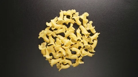 TOP VIEW: Figural macaroni shake on a black table (stop motion) Stock Footage 69810064