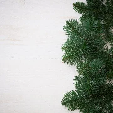 Top view of the fir branches lying on a white wooden table. Christmas mood. C Stock Photos