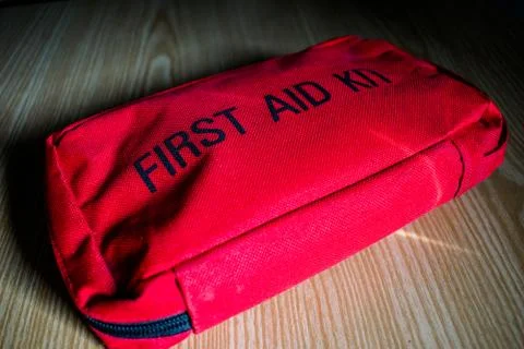 Top view of a first aid kit in red color kept on a wooden floor in a dark room Stock Photos