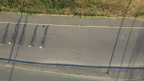 Top view five bicyclist riding bikes in line with shadow, bridge drone footage Stock Footage 79802633
