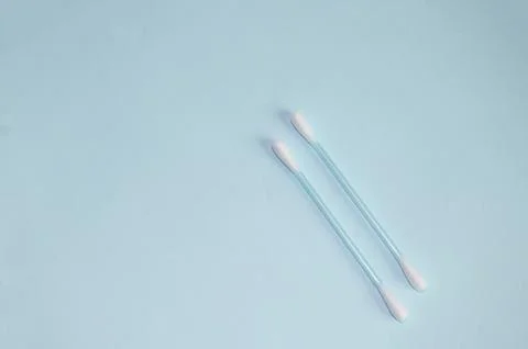 Top view, flat bed, two plastic cotton swabs neatly arranged on a pale blue b Stock Photos