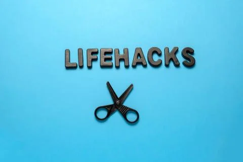 Top view flat lay black letters inscription lifehacks and scissors on a blue  Stock Photos