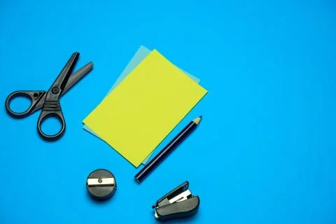 Top view flat lay blank yellow paper black scissors, sharpener, stapler and p Stock Photos