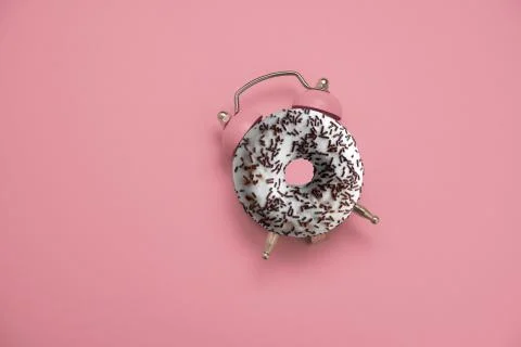 Top view flat lay creative art collage donut and alarm clock on a pastel pink Stock Photos
