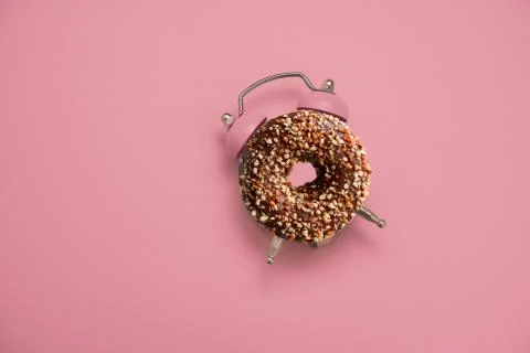 Top view flat lay creative art collage donut and alarm clock on a pastel pink Stock Photos