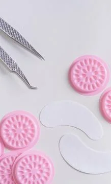 A top view flat lay featuring silver professional lash tweezers, white hydrog Stock Photos
