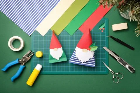 Top view flat lay of handmade paper gnomes on green craft workspace with scis Stock Photos