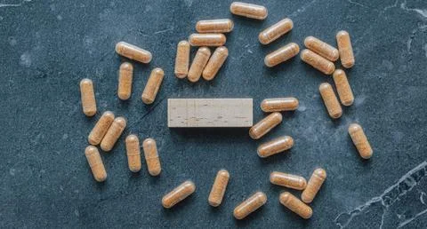 Top view flat lay of herbal brown pill capsules scattered around blank wood.. Foto stock