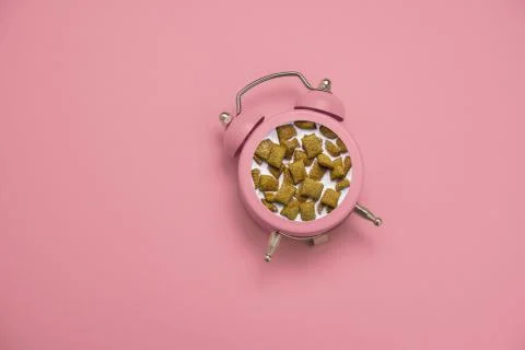 Top view flat lay pink alarm clock with a breakfast of crunchy pillows and mi Stock Photos