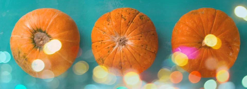 Top view flat lay three pumpkins on a blue background with shiny bokeh banner Stock Photos