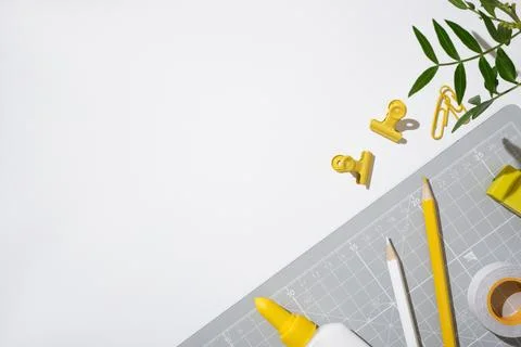 Top view flat lay of yellow office stationery on a grey cutting mat and white Stock Photos