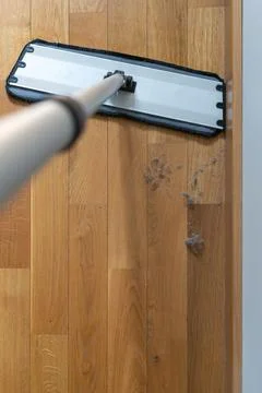 Top view of a flat mop approaching visible dust on a wooden floor Fotos de archivo