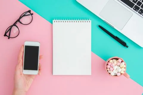 Top view flatlay blank notepad with notebook, glasses and holding phone at pink Stock Photos