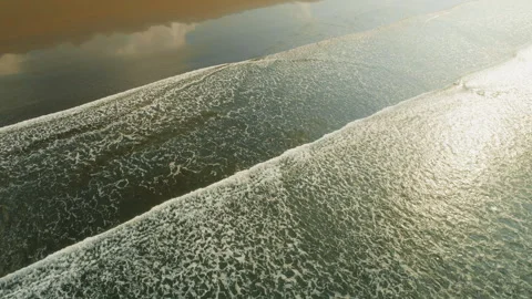 Top view of foaming ocean waves rolling over dark sand on a tropical shore Stock Footage 344703247