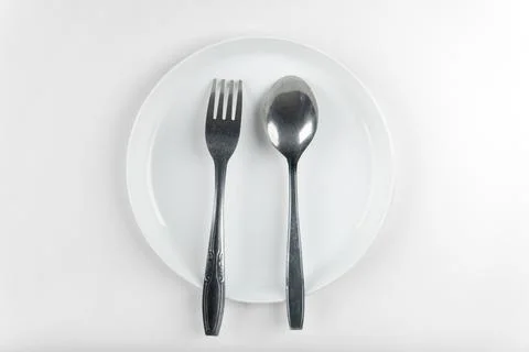 Top view fork and spoon on white plate isolated white background Stock Photos
